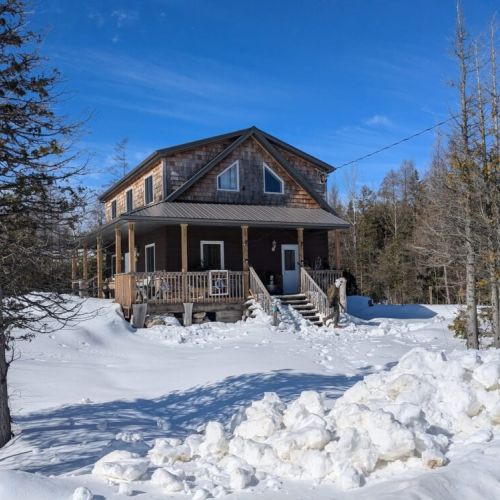 Sunny Meadow Place in winter—blanketed in snow and glowing under clear skies. A peaceful winter retreat in true Canadian cottage style.
