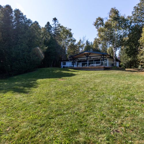 Big open lawn surrounded by trees for privacy and a peaceful cottage feel.