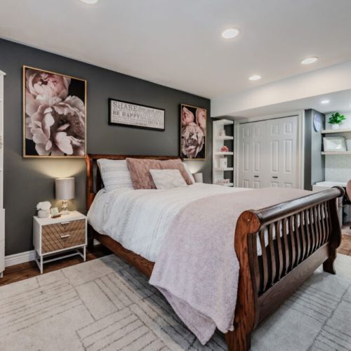 Inviting bedroom with a classic wood bed, curated art, and cozy accents—designed for a peaceful night’s rest in style.