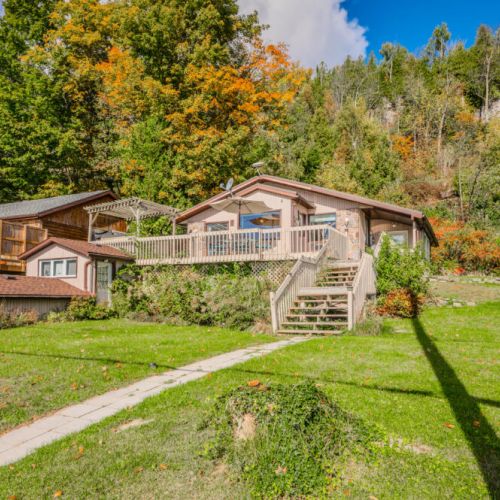 A welcoming view of Blue Moon Cottage Retreat, surrounded by lush greenery and vibrant fall colors, offering a serene escape in the heart of nature.