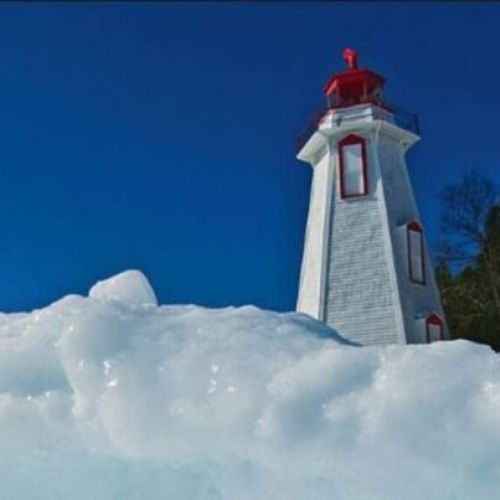 Visit a historic lighthouse surrounded by sparkling ice — a must-see highlight during your vacation adventure.
