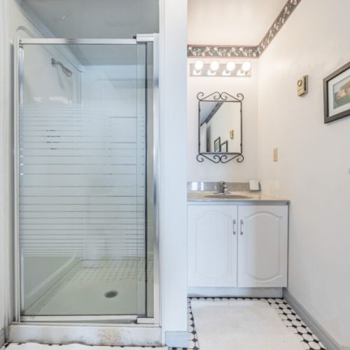 The lower level bathroom with shower. A sleek bathroom with a large mirror and vanity, offering a fresh and clean look.