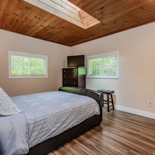A peaceful master bedroom with a queen-sized bed, natural wood paneling, and skylights that let in plenty of natural light. Relax and recharge in this serene environment