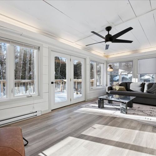 Sun-filled main living area with large windows and doors leading outside. A relaxing space to lounge, watch movies, or enjoy the natural light all day.