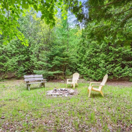 Tucked behind a stand of trees is a cozy fire circle with classic Muskoka chairs and a heart-carved bench. This is the place for late-night laughs, marshmallow roasting, and quiet reflection under the stars.