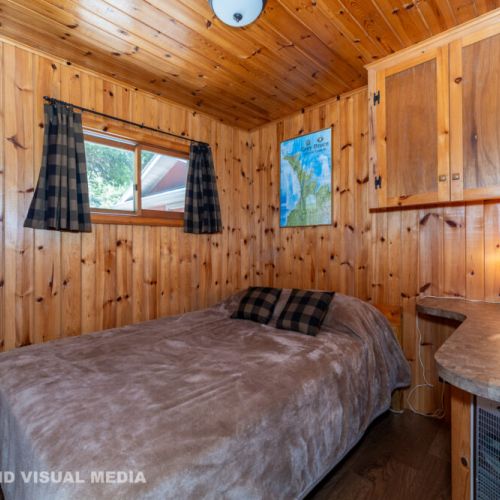 Another comfortable wood-lined bedroom with built-in storage and soft lighting — perfect for unwinding.