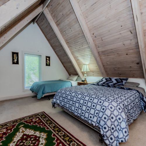 The loft-style bedroom offers unique angled ceilings and stunning views, making it a cozy retreat for rest and relaxation.