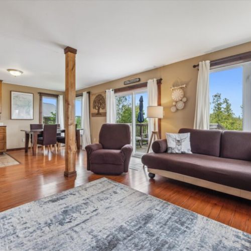 Bright and airy main living space with access to the deck—enjoy natural light, soft curtains, and comfortable seating throughout.