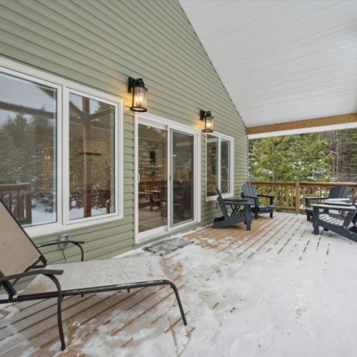 Spacious front deck with seating for outdoor dining, relaxing evenings, and enjoying the peaceful woodland setting.