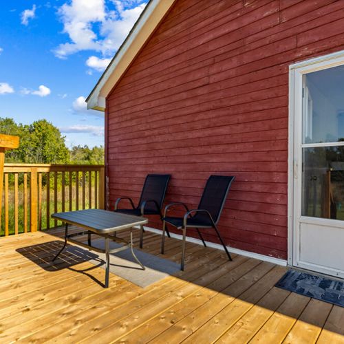 Relax on the spacious new deck with comfortable outdoor seating and peaceful views across the property.