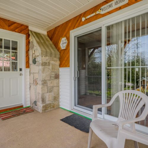 Step onto the cozy porch, where a comfortable chair and the charming decor create an ideal spot to enjoy a morning coffee or an evening breeze. The warmth of the cottage begins here.