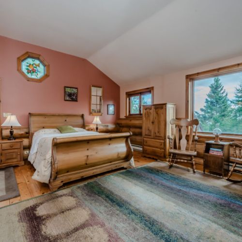 This bright and spacious bedroom offers a tranquil seating area and large windows that frame beautiful views of the surrounding landscape, perfect for relaxation and quiet moments.