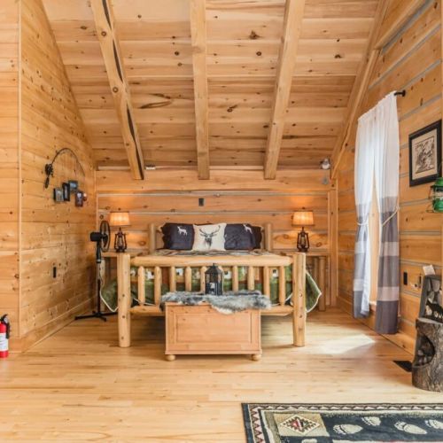 The second semi-private bedroom in the loft provides a cozy retreat with handcrafted log furniture and rustic decor, ensuring a restful night's sleep.
