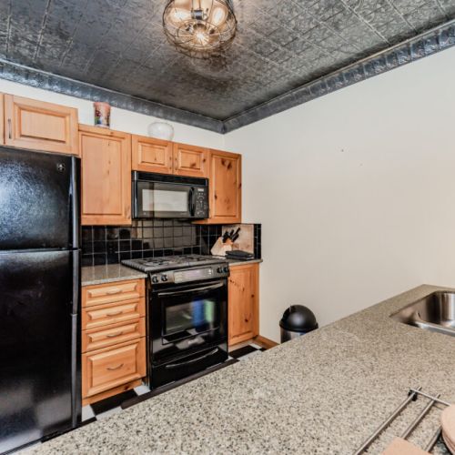 Fully equipped kitchen with black appliances, granite countertops, and rustic wood cabinetry—perfect for cooking during your forest getaway.
