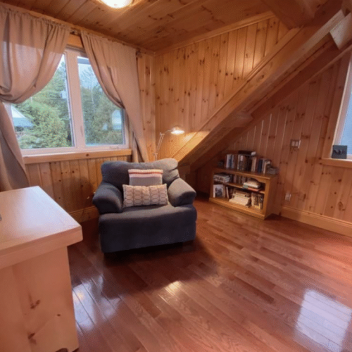 Relax with a good book in this peaceful reading corner, complete with a plush armchair and natural lighting from large windows.