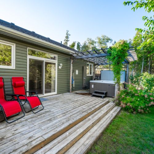 Unwind in the sunshine with lounge chairs and a private hot tub on this spacious backyard deck—an ideal escape for your next cottage getaway.