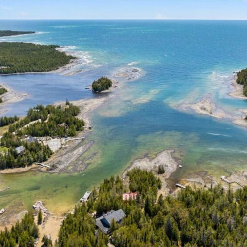 Stunning bird’s-eye view showcasing the beautiful turquoise waters and scenic waterfront landscape surrounding the cottage.