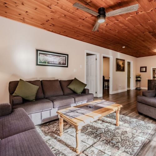 Relax in our comfortable and cozy living room, featuring plush seating and a warm wood-paneled ceiling. The perfect place to unwind after a day of exploring.