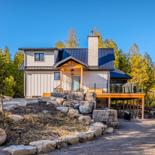 Stylish modern cottage with beautiful stone landscaping and large outdoor deck—perfect for BBQs, fireside lounging, and unforgettable vacation stays by the lake.