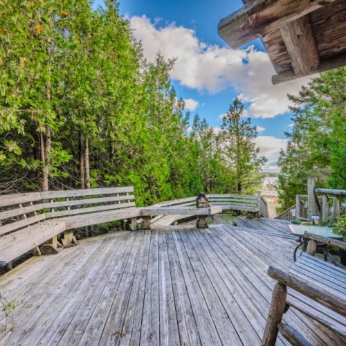 This inviting wraparound deck is nestled within a canopy of trees, offering a serene and private setting to relax and connect with nature.
