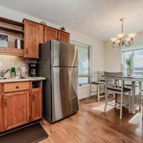 The dining area, set beside large windows, offers breathtaking lake views while you enjoy your meals. A comfortable seating arrangement around the dining table makes it ideal for family breakfasts or intimate dinners, all while soaking in the beauty of the surroundings.