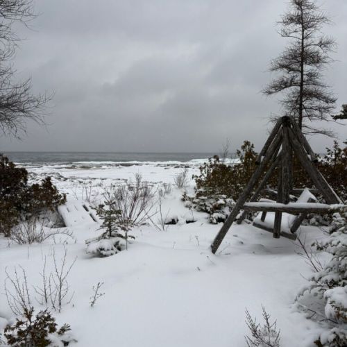 Snow-dusted seating overlooks the lake and rugged shoreline, creating a peaceful spot to unwind. A year-round destination for travellers seeking comfort, scenery, and nature-focused escapes.