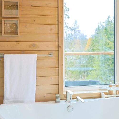 Unwind in this spa-like bathroom, featuring a luxurious soaking tub and stunning views of the surrounding nature. The warm wood accents and natural light create a peaceful and relaxing atmosphere.