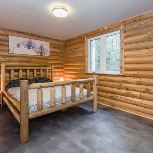 Main floor Master bedroom; cozy enough for a King, and captures the essence of cabin living, focusing on rest and relaxation with its understated design.