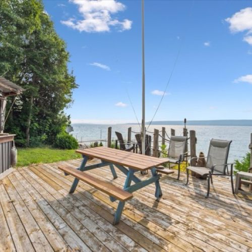 Waterfront deck with picnic table, bar area, and seating—ideal for enjoying breathtaking lake views and outdoor gatherings.