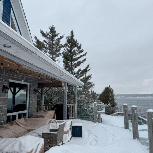 Relax and recharge at this stunning vacation rental with a snowy lakefront view and glass-railed deck for unforgettable coastal scenery.