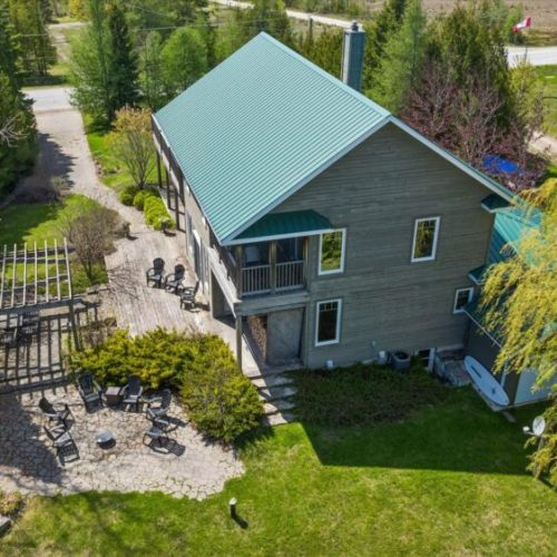 Elevated aerial perspective showcasing the cottage, patio, and surrounding landscape.