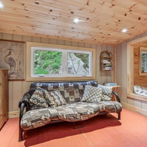 Relax on the cushioned futon with a good book, or enjoy scenic forest views through large windows. This inviting living space blends rustic charm with homey details.