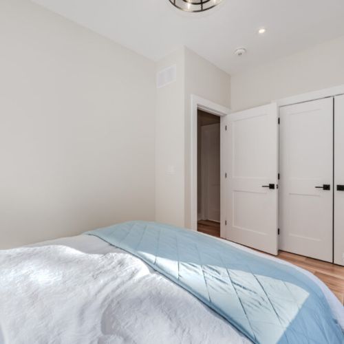 Enjoy a cozy night's sleep in this bright, stylish bedroom featuring a queen bed, soft linens, and natural light—perfect for a relaxing cottage getaway.