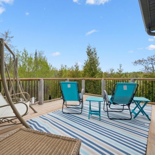 A private sunning retreat just outside the primary bedroom offers a peaceful connection to nature, with tranquil views of the surrounding landscape and glimpses of the lake in the distance.