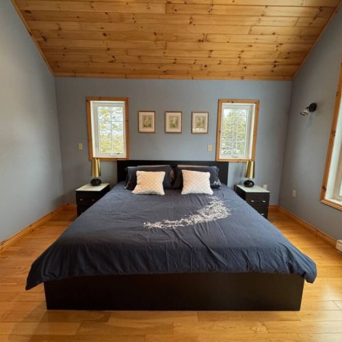 Sleep soundly in this spacious king bedroom with serene forest views and modern cottage décor—ideal for restful vacation nights.