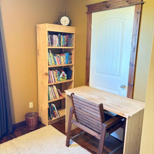Quiet corner with a writing desk and bookshelf stocked with games and books for all ages—a cozy spot for reading or relaxing.