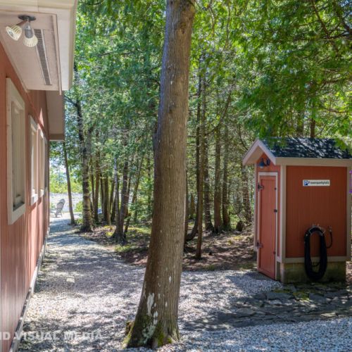 Outdoor shower/utility shed tucked among the trees—great for rinsing off after a swim.