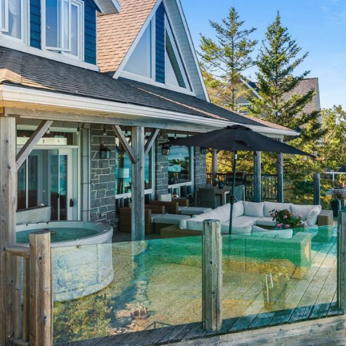 This view showcases the beautiful architecture of the Lion's Den property, nestled right on the shores of Georgian Bay, with ample outdoor seating and luxurious amenities.