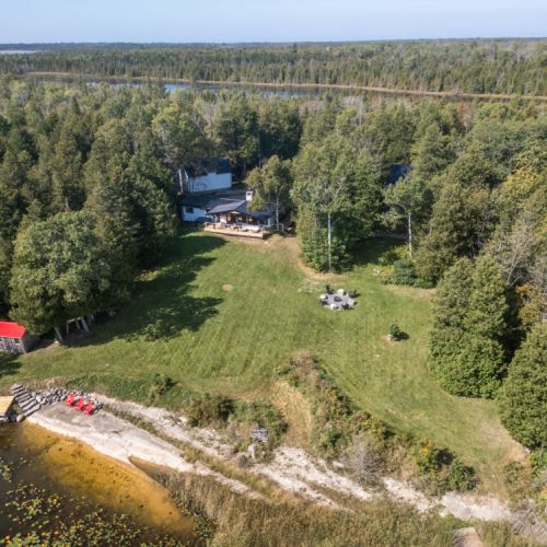 A bird’s eye view of Midnight Star showing your private waterfront, big grassy yard, and peaceful tree-lined setting on Stokes Bay.