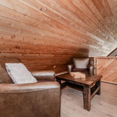 Cozy loft lounge area featuring comfy leather chairs and wooden accents, the perfect spot to unwind after a day exploring the lake and trails.