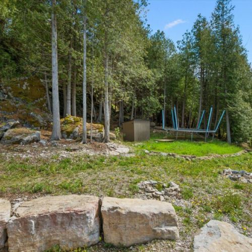 A fenced natural area bordering the property contributes to the cottage's private, forested atmosphere.