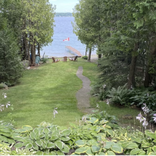 The sprawling backyard leads to the lapping shores of the bay, a peaceful place to embrace nature that is surrounded with trees for privacy.