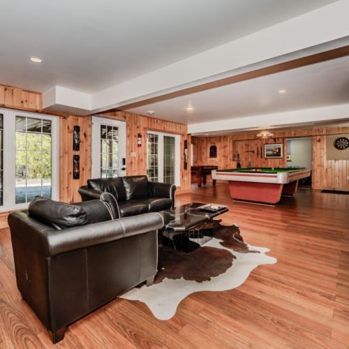 Lower-level entertainment lounge with leather seating, smart TV, and rustic charm – great for movie nights or rainy day fun.