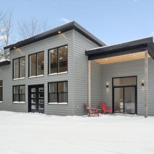 Contemporary cottage exterior with covered entry, large windows, and modern design.