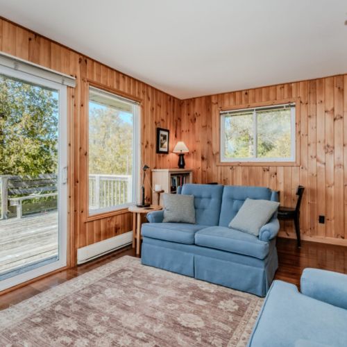Cozy seating area with rustic charm and access to a large private deck — perfect for morning coffee or sunset views by the lake.