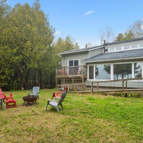 Spacious waterfront cottage with large windows and a sunny yard overlooking the lake.
