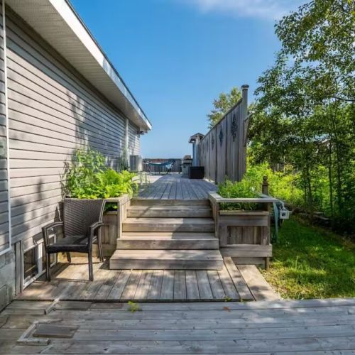 A side view of the cottage showing easy access to the expansive deck — perfect for seamless indoor-outdoor living.