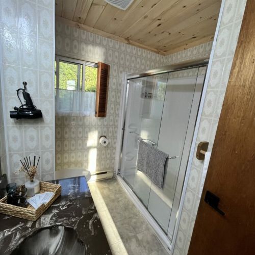 A clean and modern bathroom featuring a spacious shower, elegant countertop, and wooden ceiling, creating a comfortable and inviting space.