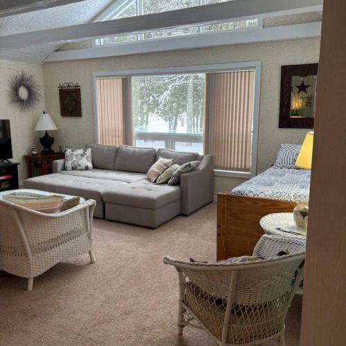 Another view of the main space showing the bright windows and comfortable cottage furnishings.