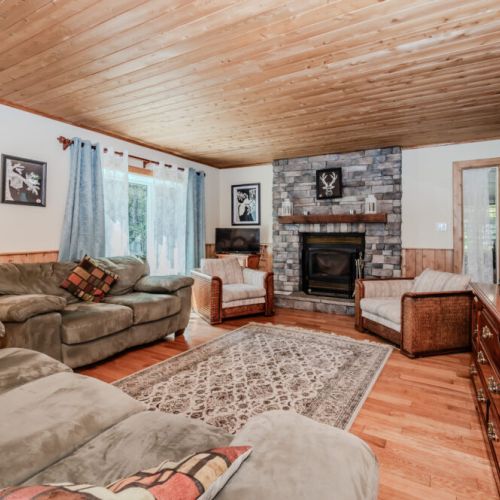Cozy up by the stone fireplace in a rustic-chic living room. A warm and inviting space for year-round cottage comfort and romantic escapes.